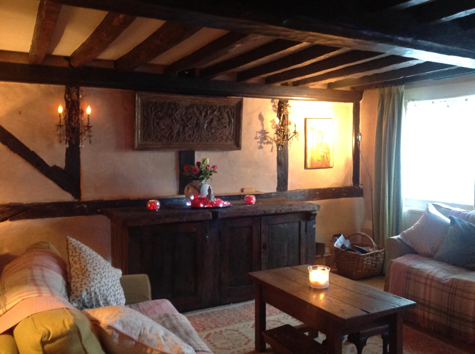 Warm, characterful living room with exposed beams, antique furniture and soft lighting